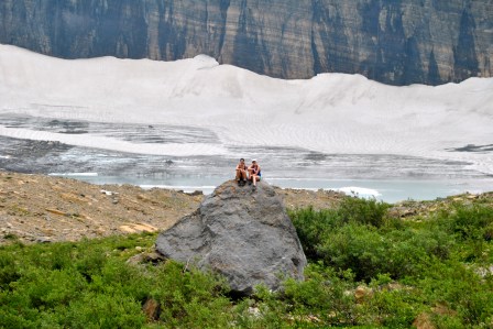 Allie Goldstein and Kirsten Howard atop a rock in front of Grinnell Glacier, which is retreating (melting) quickly.